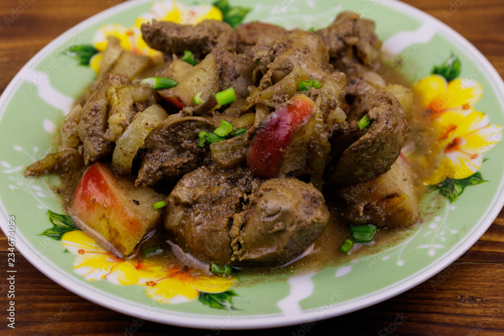 Stewed chicken liver with apple and onion on wooden table Stewed chicken liver with apple and onion on wooden table
