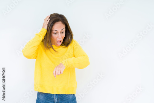 Beautiful middle age woman wearing yellow sweater over isolated background Looking at the watch time worried, afraid of getting late © Krakenimages.com