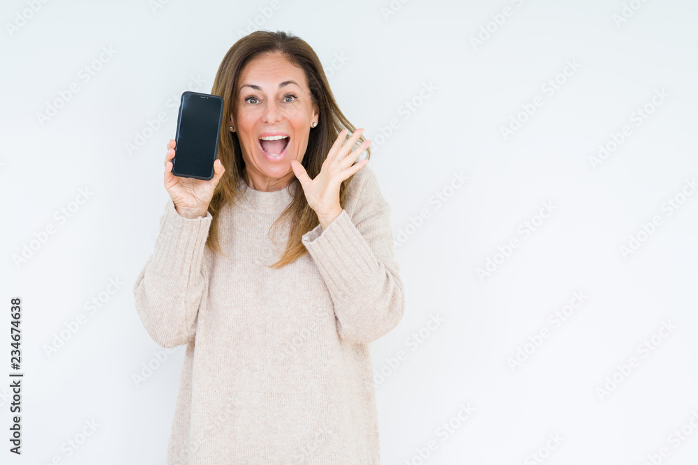Middle age woman showing smartphone screen over isolated background very happy and excited, winner expression celebrating victory screaming with big smile and raised hands Middle age woman showing smartphone screen over isolated background very happy and excited, winner expression celebrating victory screaming with big smile and raised hands