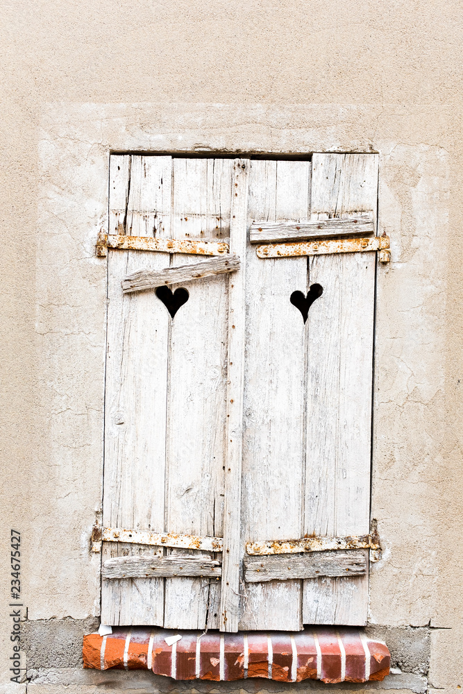 old weathered gray shutters windows with heart shaped holes in ancient wall