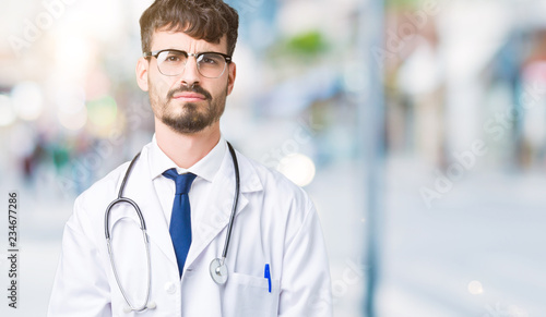 Young doctor man wearing hospital coat over isolated background depressed and worry for distress, crying angry and afraid. Sad expression.