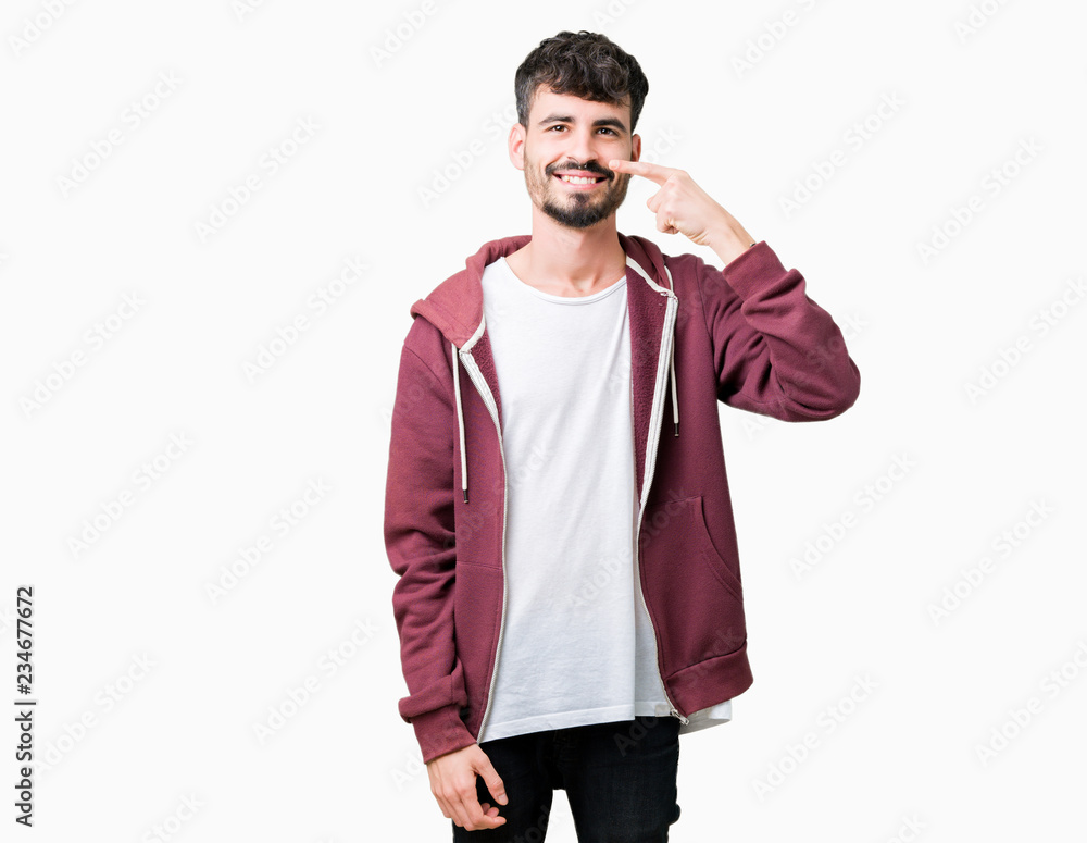 Fototapeta premium Young handsome man over isolated background Pointing with hand finger to face and nose, smiling cheerful