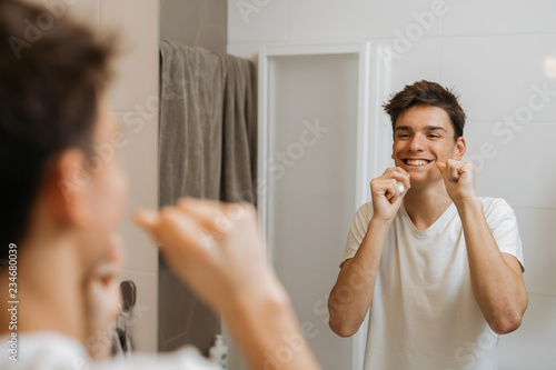 Quadro em tela teenager boy cleaning his teeth with dental floss in his bathroom
