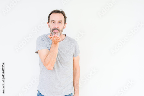 Handsome senior man over isolated background looking at the camera blowing a kiss with hand on air being lovely and sexy. Love expression.