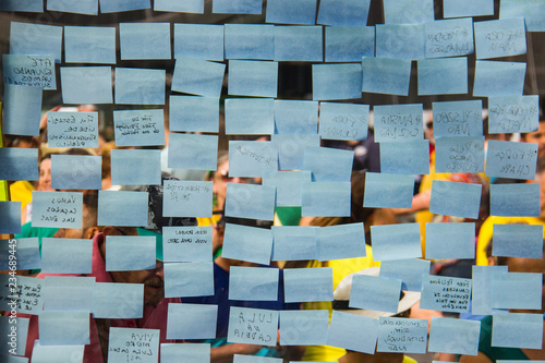Blue post-it sticky notes on a glass wall.