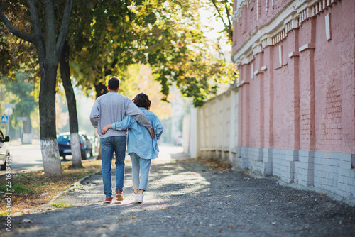 Back view of hugging couple walking on street