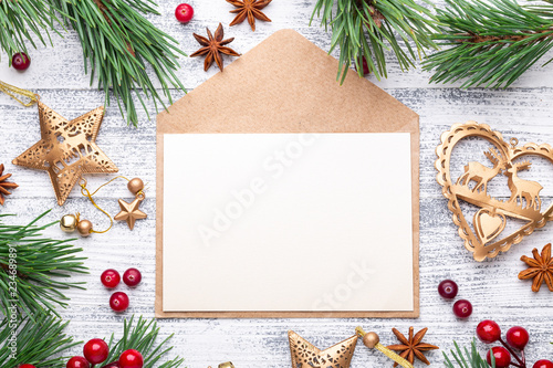Fir branches, gifts and an envelope on a light wooden background. Cranberries, spices, holly berries.