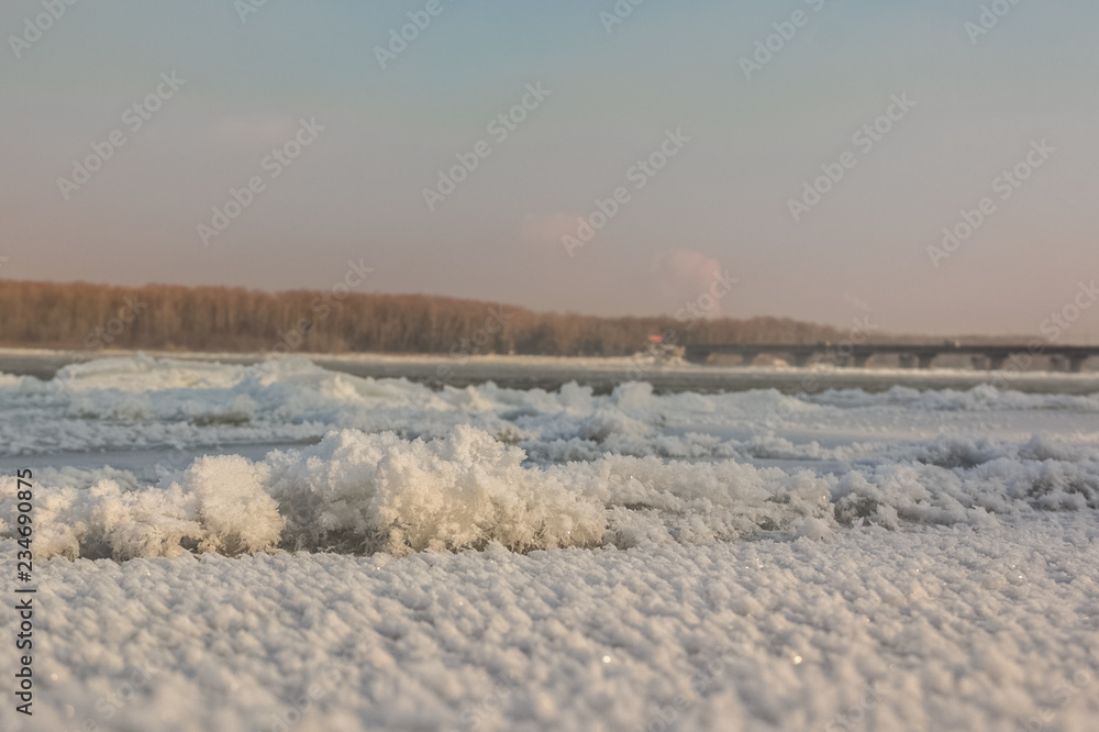Pile of ice floes on the river at the beginning of winter and in the distance can be seen automobile bridge.