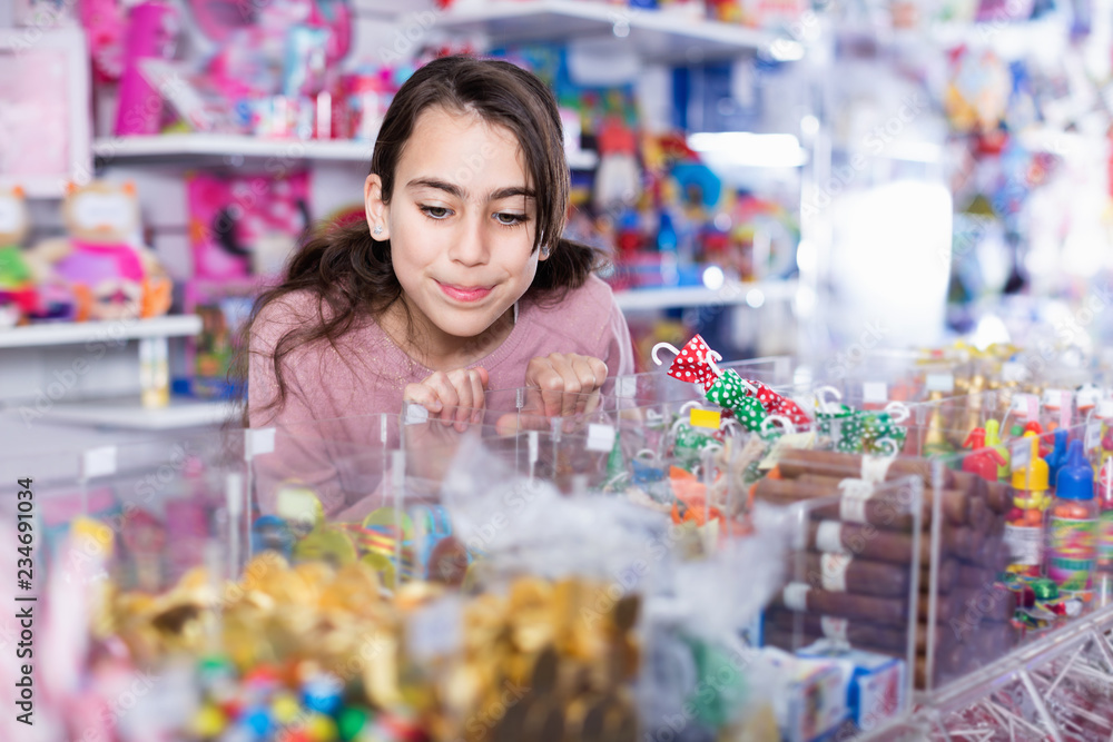 Emotional small girl choosing sweet candies in the candy shop