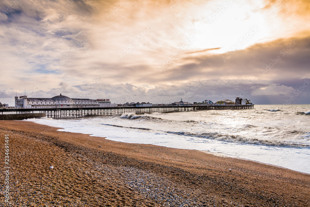 famous Brighton Pier, Beach and Ocean with high waves in front of dynamic sky activities 