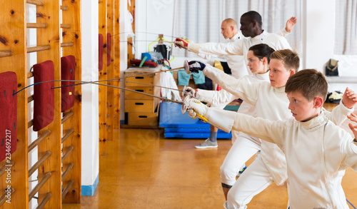 Group practicing fencing techniques in gym