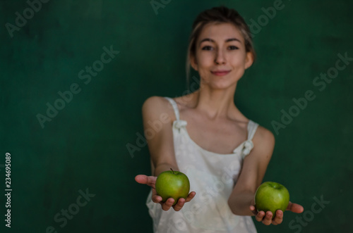 young woman in white suit posing and holding apples