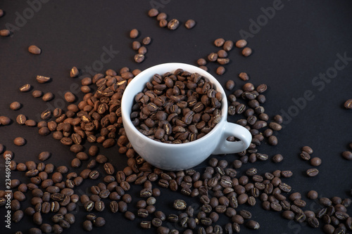 Close up of coffee cup in coffee beans on black background.