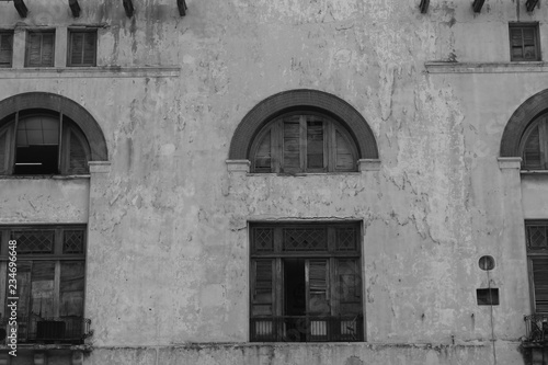 Old, Spanish style cement building, Havana, Cuba. Arched window frames, broken shutters and doors, chipped and pealing paint. Black and White