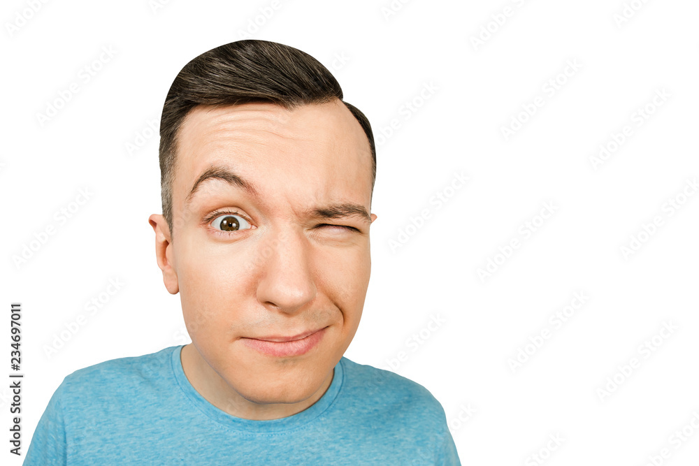 Fototapeta premium Portrait of young guy with closing one eye isolated on a white background.