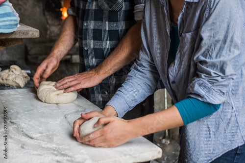Woman and man shaping dough for bread