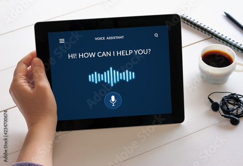 Hand holding tablet with voice assistant concept on screen