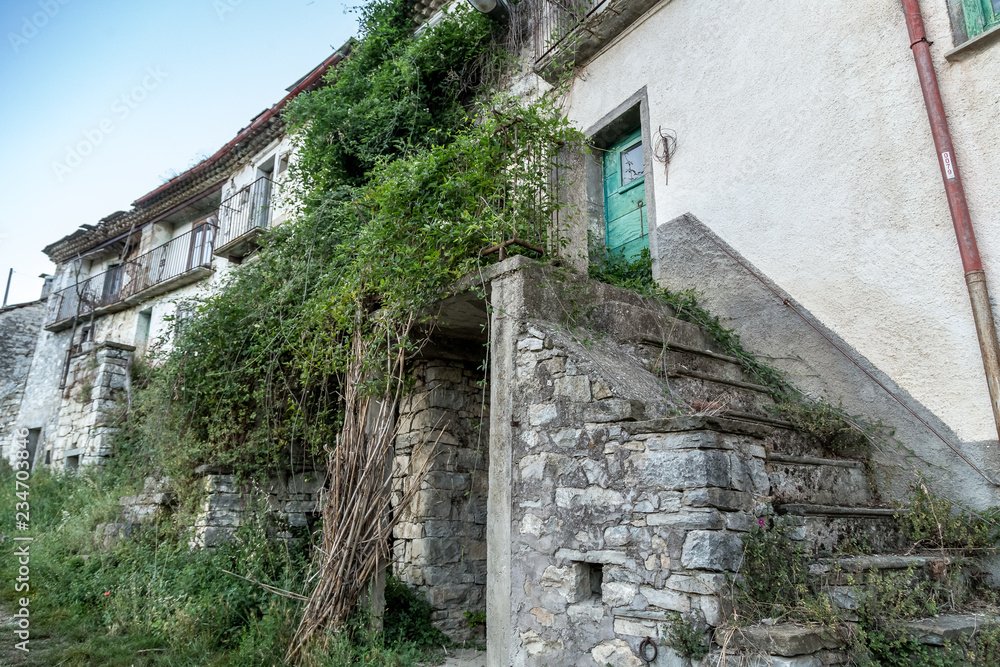 An old abandoned house in Agnone with green garden leaves, Italy.