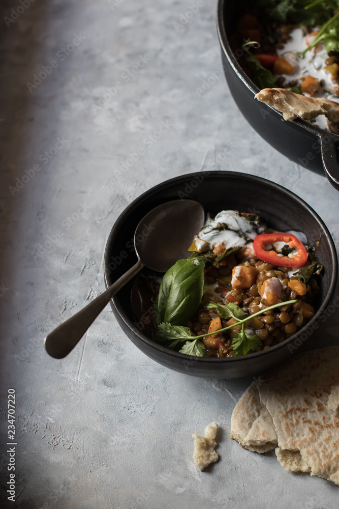 Bowl near pot with ragout of lentil and sweet potato curry Bowl near pot with ragout of lentil and sweet potato curry