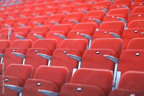 Rows of red numbered seats with armrests in a large auditorium