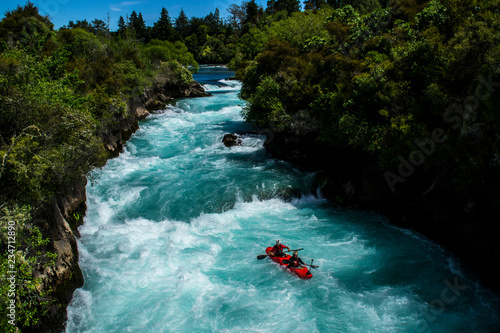 Travel New Zealand. Most popular tourist attraction Huka Falls at Lake Taupo, North Island. White and turquoise water, green forest on background. Beautiful landscape view. Active summer holidays. 