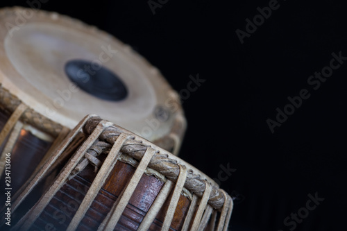 Tableau sur toile Images of a man's hands (wearing beads) playing the Tabla - Indian classical music percussion instrument - black background