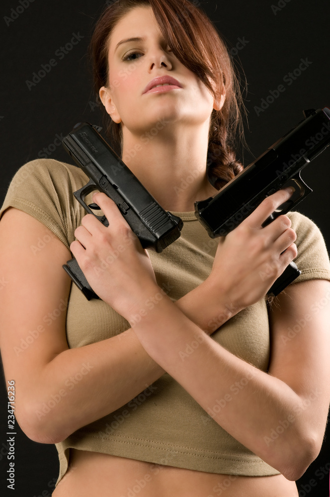 Young woman holding two guns across her chest Young woman holding two guns across her chest