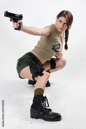 Young brunette woman with two guns squatting down