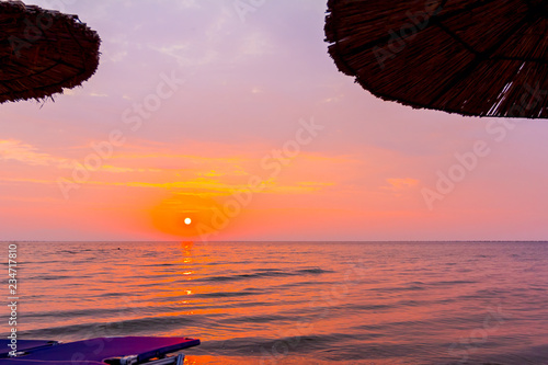 Morning light over umbrellas with loungers  chaise are placed next to the coastline  along water edge