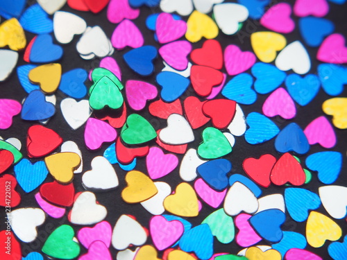 Small colorful shiny hearts on a black background.