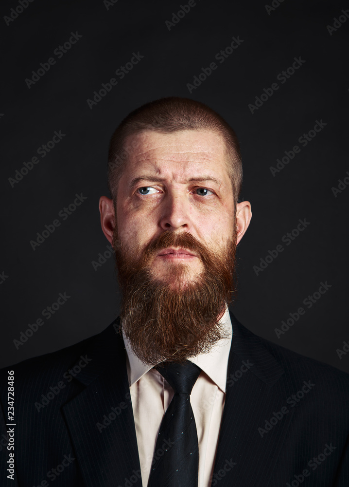 Serious , bearded man in white shirt and classic, elegant jacket on dark background. Serious , bearded man in white shirt and classic, elegant jacket on dark background.