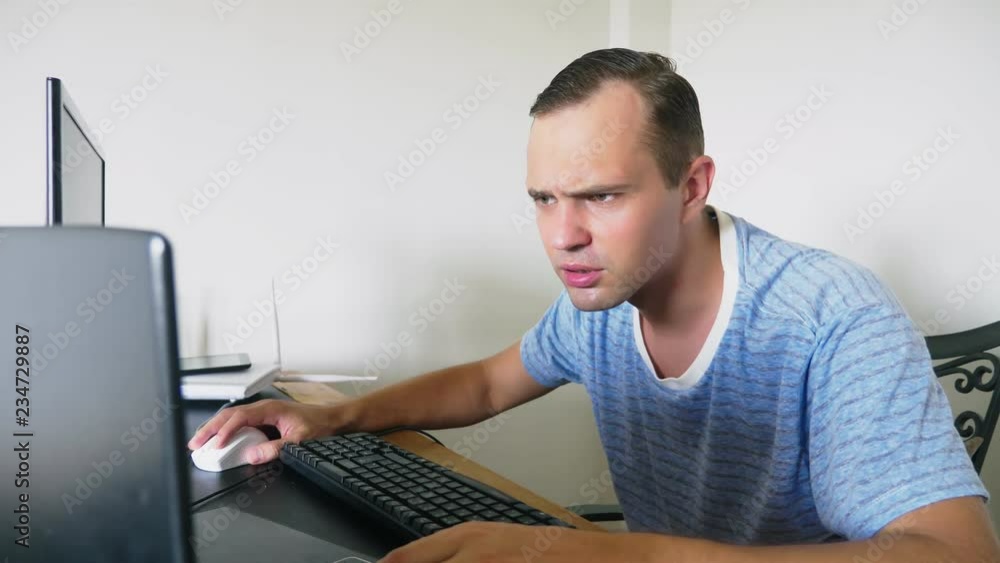 A man sitting at a desk at home, working at home computer and laptop. A man sitting at a desk at home, working at home computer and laptop.