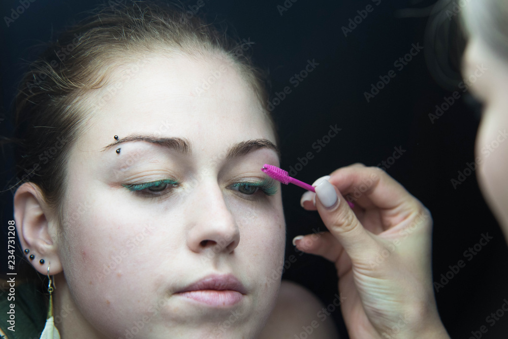 Obraz premium Eye lash extension procedure. Young beautiful woman eye with long false green eye lashes. Close up macro shot of fashion eyes in beauty salon.