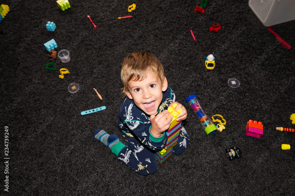 Naklejka premium happy boy playing with toys, top view