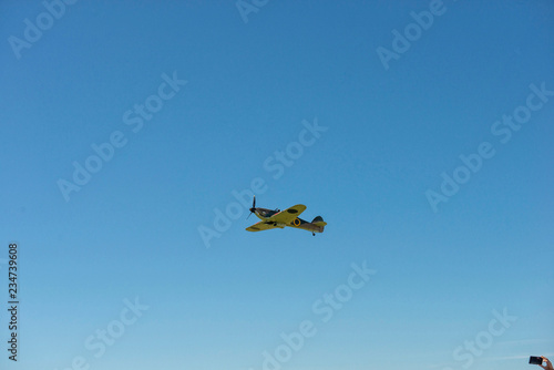 Propellerflugzeug Oldtimer fliegt über den Himmel in der äußersten Ecke eine Hand mit Handy auf das Flugzeug gerichtet um zu fotografieren