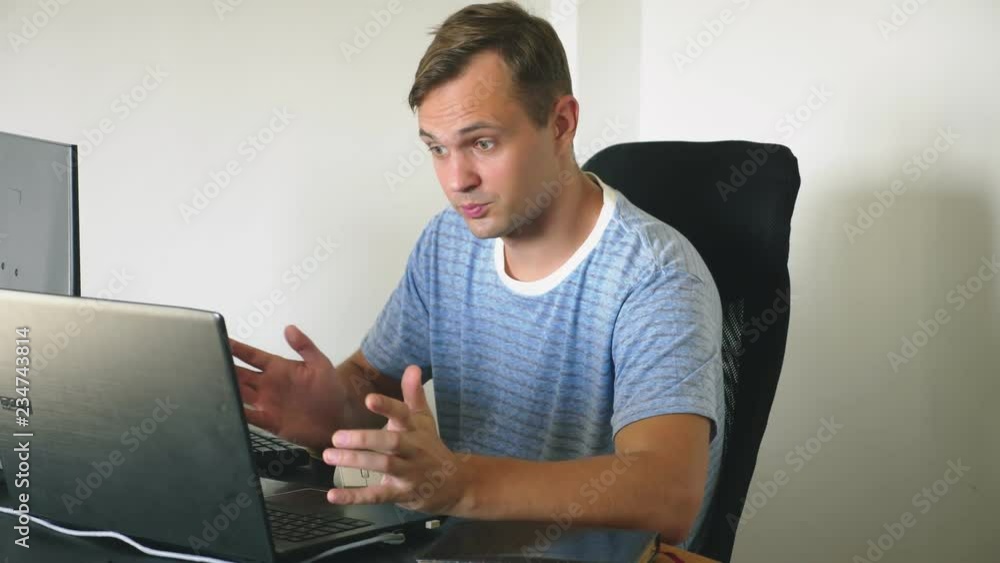 A man sitting at a desk at home, working at home computer and laptop. A man sitting at a desk at home, working at home computer and laptop.