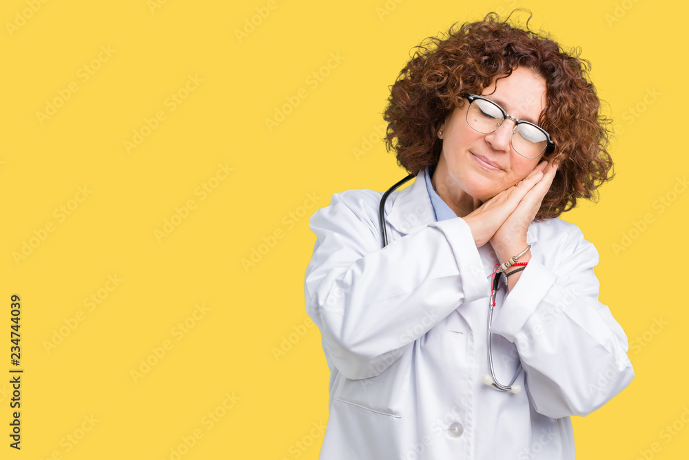 Middle ager senior doctor woman over isolated background sleeping tired dreaming and posing with hands together while smiling with closed eyes. Middle ager senior doctor woman over isolated background sleeping tired dreaming and posing with hands together while smiling with closed eyes.