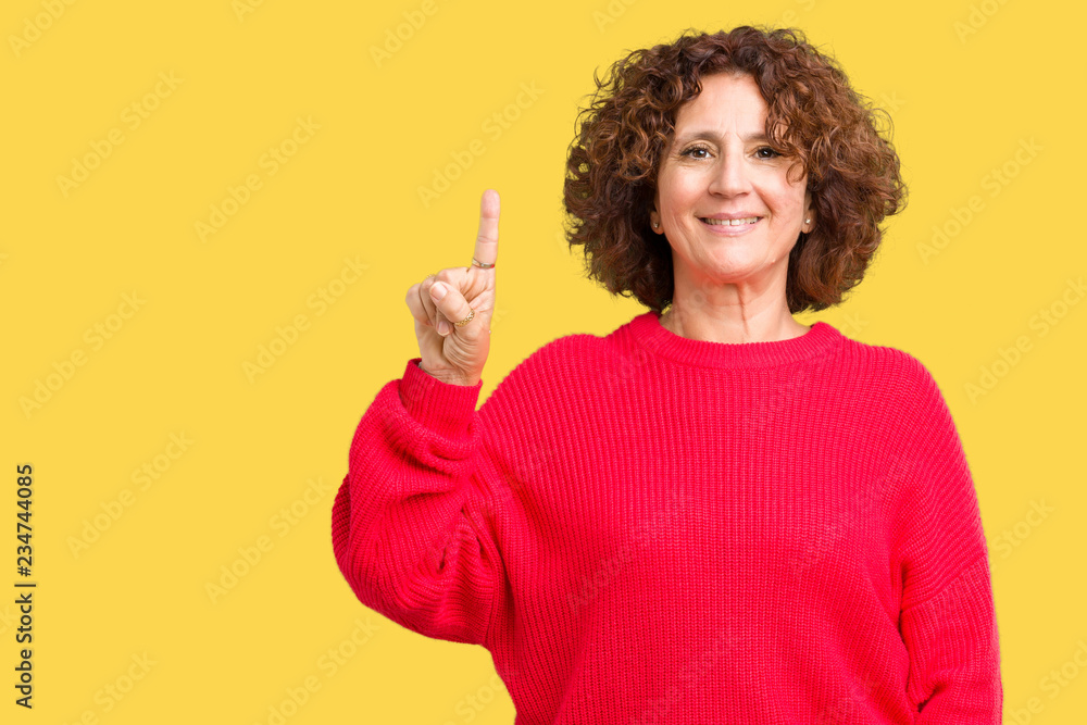Beautiful middle ager senior woman red winter sweater over isolated background showing and pointing up with finger number one while smiling confident and happy. Beautiful middle ager senior woman red winter sweater over isolated background showing and pointing up with finger number one while smiling confident and happy.
