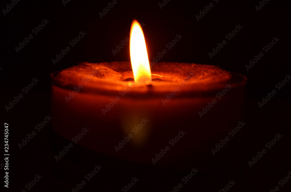 Burning yellow flame red candle on a dark background. Burning yellow flame red candle on a dark background.