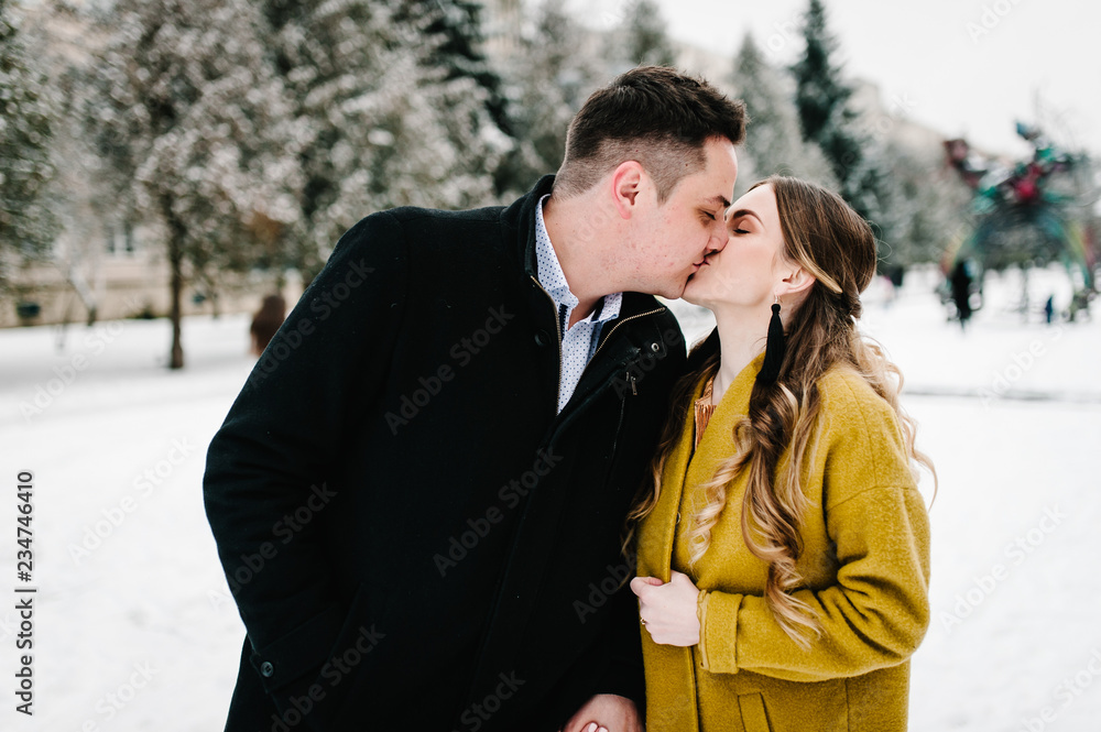 Happy couple enjoying, hugging and kiss near christmas tree, outdoors in winter. Man and woman, season, love and leisure concept. Happy couple enjoying, hugging and kiss near christmas tree, outdoors in winter. Man and woman, season, love and leisure concept.