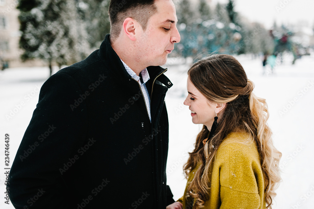 Young couple in love holding hands outdoor. Man and woman walk on a snowy winter park in love and leisure concept. Young couple in love holding hands outdoor. Man and woman walk on a snowy winter park in love and leisure concept.