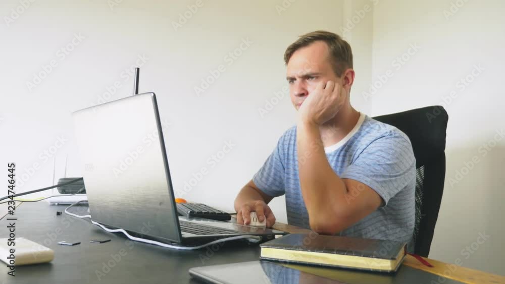 A man sitting at a desk at home, working at home computer and laptop. A man sitting at a desk at home, working at home computer and laptop.