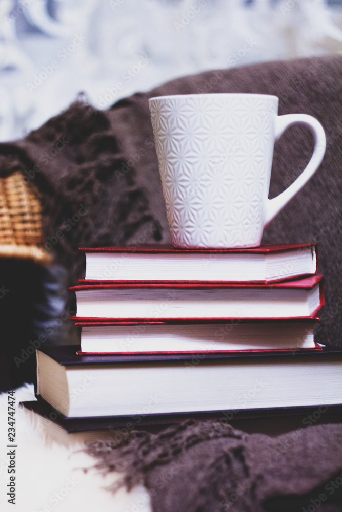 Naklejka premium white Cup stands on a pile of books on the bed