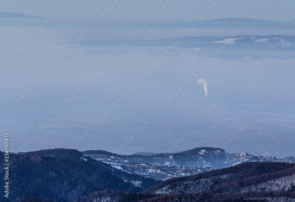 Φωτογραφία Winter mountain landscape with snowy foggy Brasov city in the evening, as seen from Postavaru peak, Poiana Brasov, Romania