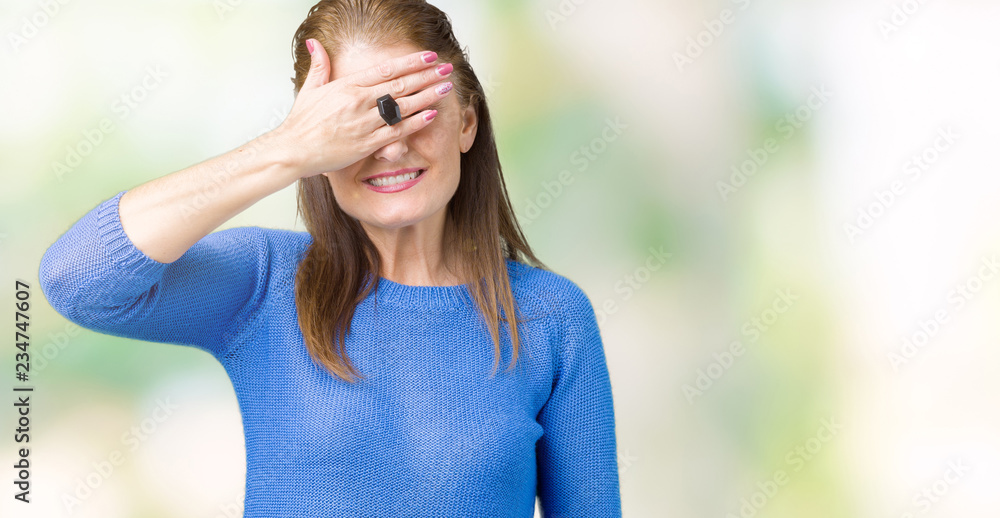 Beautiful middle age mature woman wearing winter sweater over isolated background smiling and laughing with hand on face covering eyes for surprise. Blind concept. Beautiful middle age mature woman wearing winter sweater over isolated background smiling and laughing with hand on face covering eyes for surprise. Blind concept.