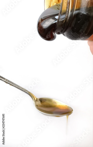 close-up silvery and vintage spoon with honey falling, on white background