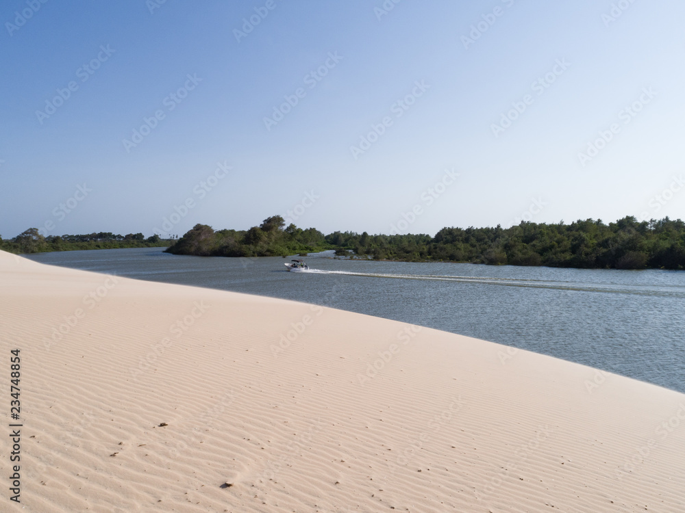Amazing white dune, sand texture , boat passing by, blue sky pastel color, Brazil, Parnaíba.	