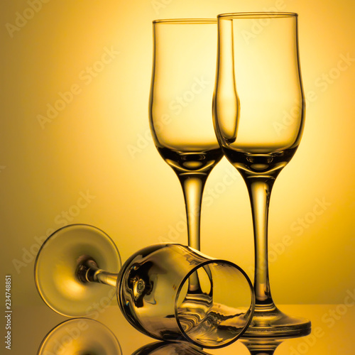 Three empty champagne glasses on colored background with reflection. Advertising image art toned
