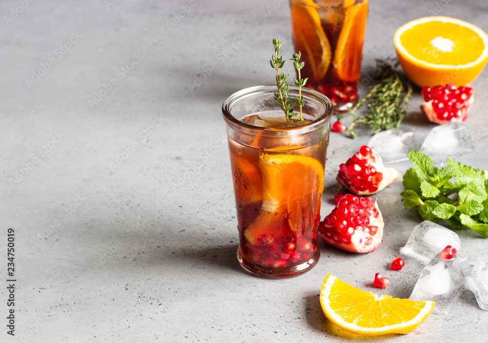 Cold lemonade or festive cocktail with pomegranate, mint and orange. Grey concrete background. Copy space. Cold lemonade or festive cocktail with pomegranate, mint and orange. Grey concrete background. Copy space.