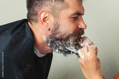 Portrait of male client getting his beard washed at salon. Cleaning beard barber's. Man at barbershop. Hairdresser washing beard to her handsome client. photo